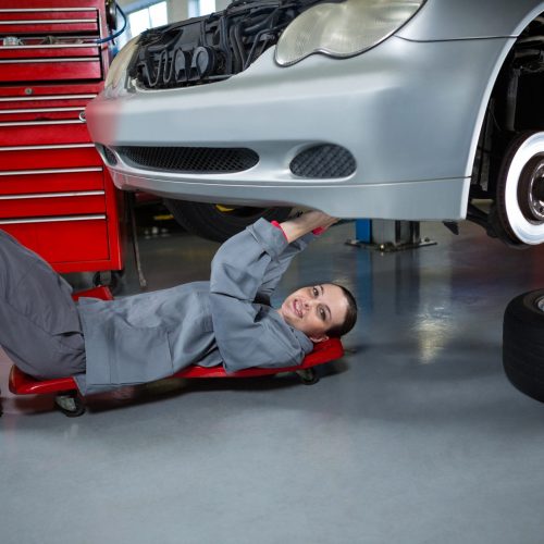 Portrait of beautiful female mechanic repairing a car at repair garage